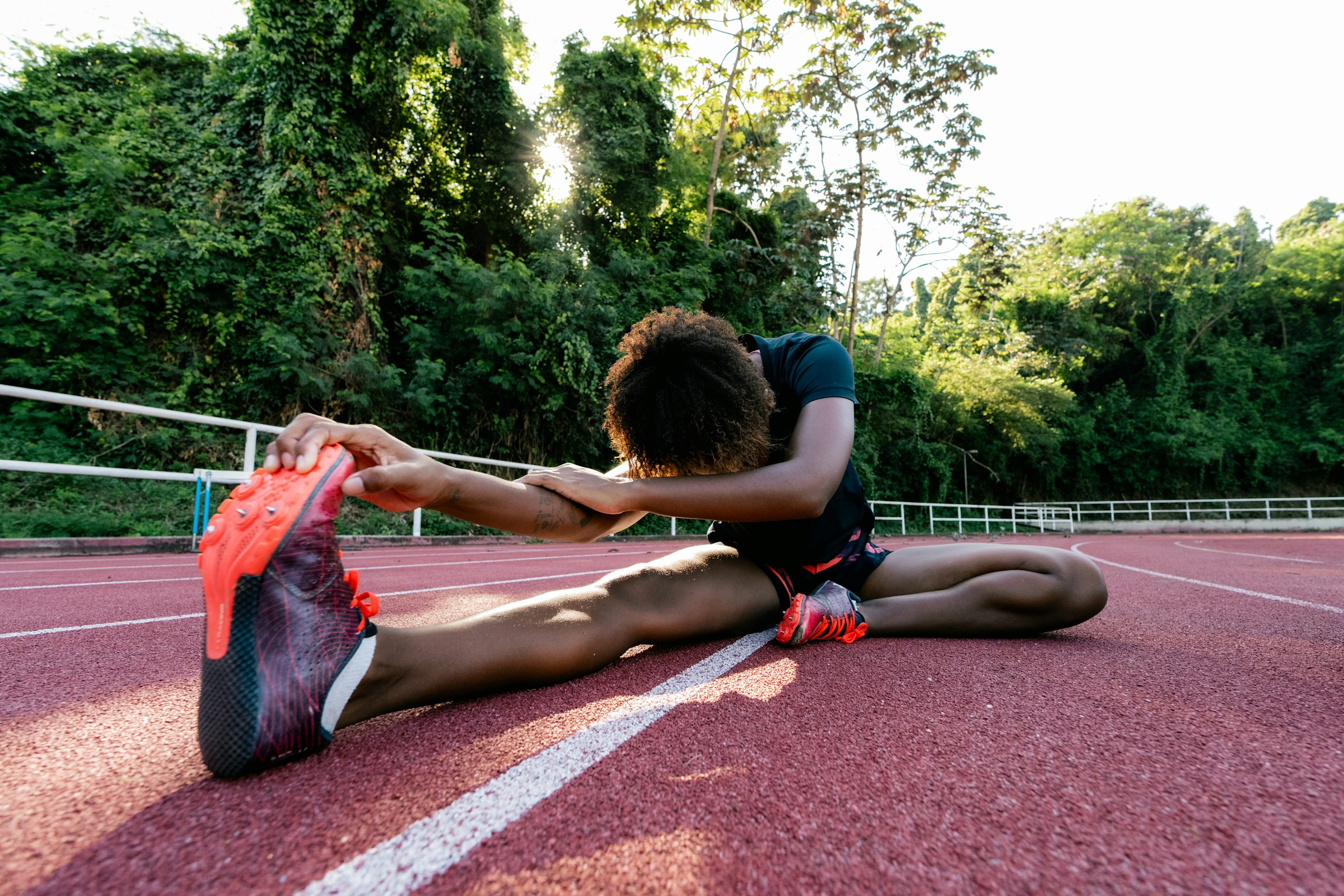 Atleta femenina estirando en pista de atletismo durante entrenamiento