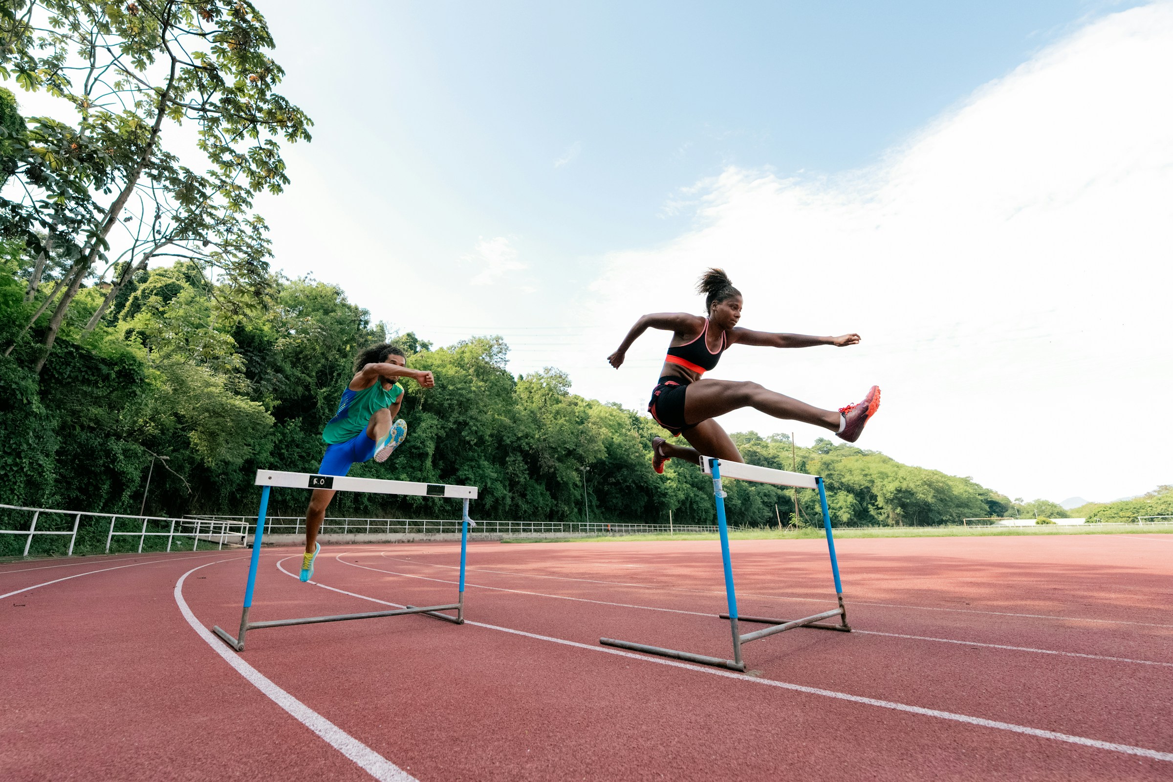 Atletas saltando vallas en pista de atletismo