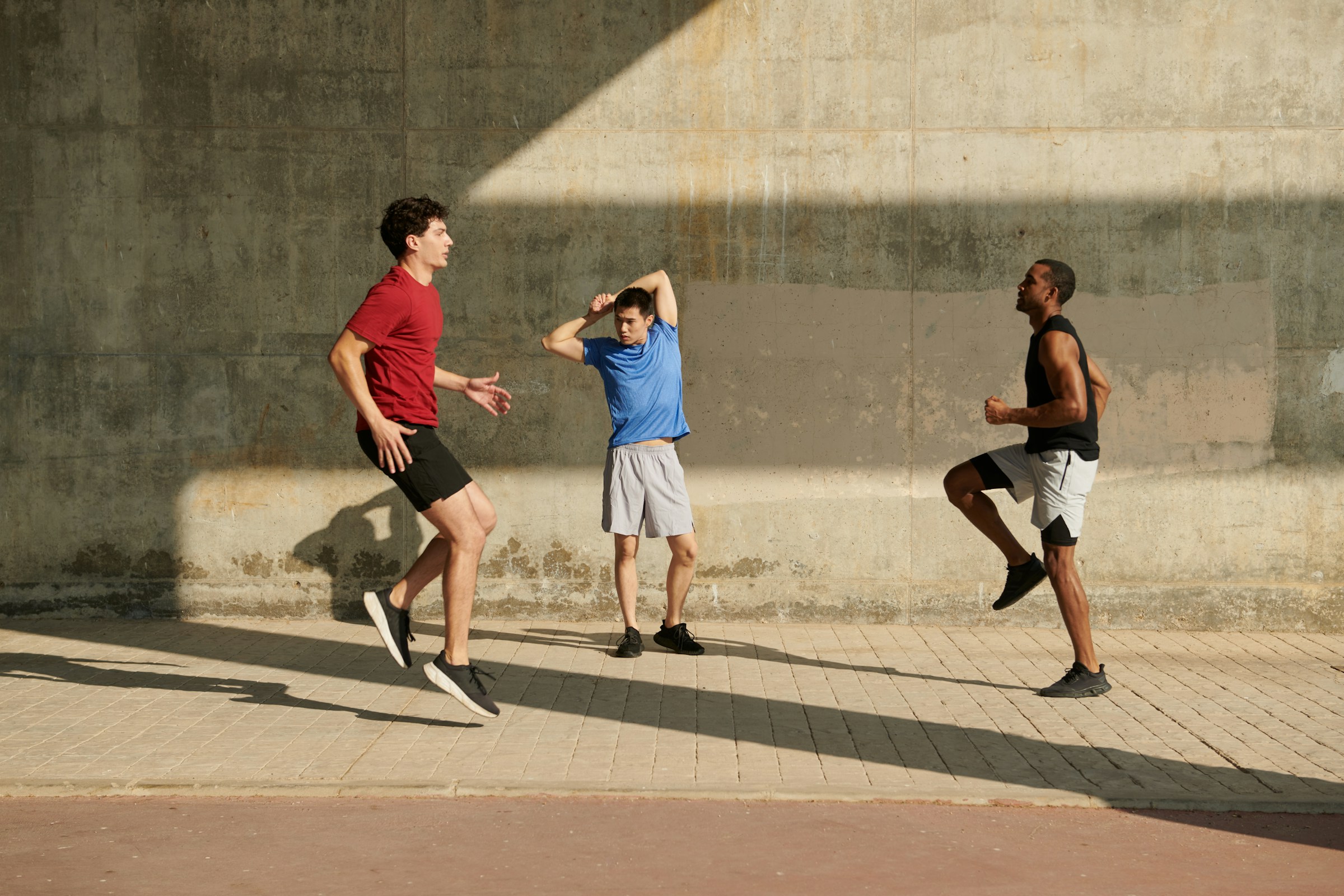 Tres atletas entrenando al aire libre contra una pared de concreto