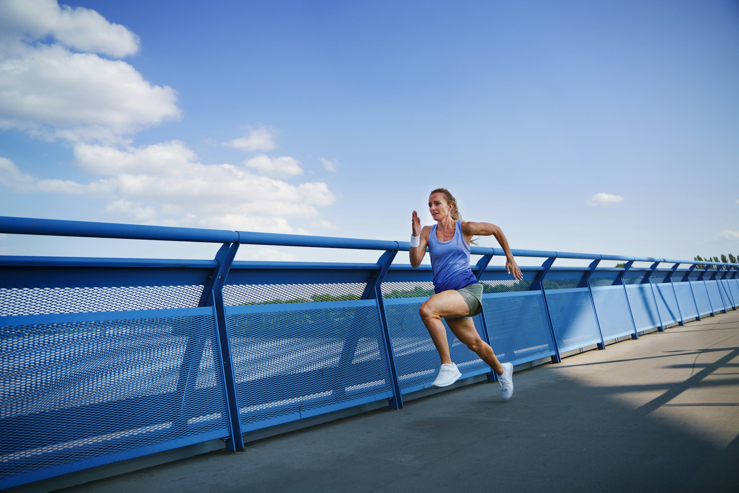 Atleta corriendo en puente con cielo azul