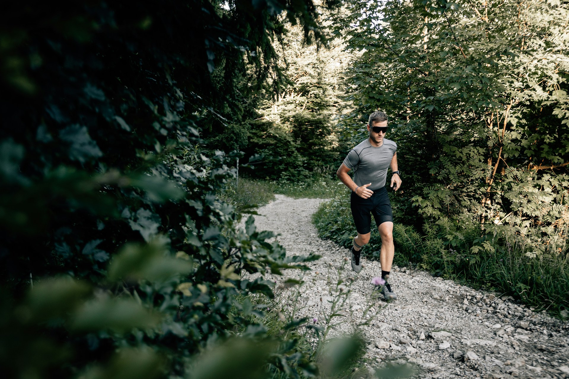 Corredor de trail en bosque con gafas de sol